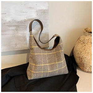 Detail of retro plaid tote bag with brown leather strap on minimalist autumn backdrop