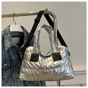 Detail of silver quilted puffer tote bag on metal hanger with a denim jacket background