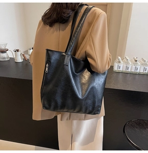 Detail of black pleated faux leather tote bag with silver zippers and spacious design