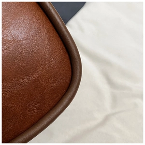Detailed close-up of brown litchi pattern leather bag with reinforced edge stitching