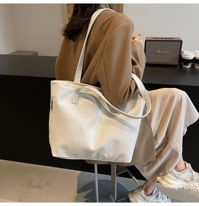Detail view of large white leather tote bag with lychee texture and side zipper