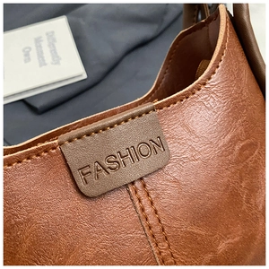 Detail of vintage brown leather bag with FASHION embossed label and stitching