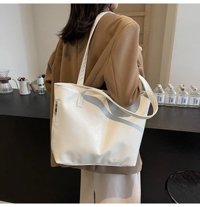 Close-up of white soft leather tote bag showing natural grain and side zipper details