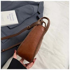 Detailed side profile view of brown vintage leather crossbody bag with spacious structure