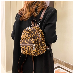 Detailed view of women's mini leopard print faux suede backpack worn on a black blazer