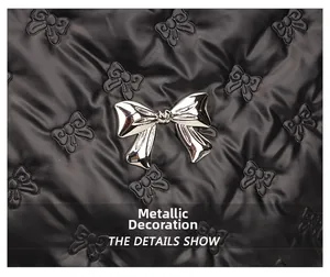 Detail of silver metal bow hardware on black quilted fabric with bow pattern texture