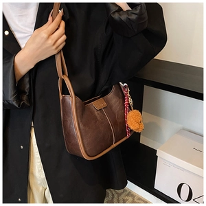 Detail of dark brown retro leather shoulder bag with bear charm and fashion plaque