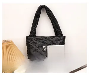 Close-up of black quilted tote bag with bow embroidery and metal bow pendant charm