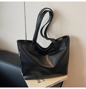 Close-up of black PU leather tote bag with fine texture and silver zipper detail