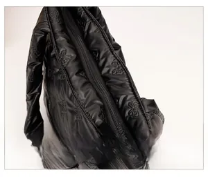 Detail of smooth metal zipper closure on black quilted butterfly embossed tote bag