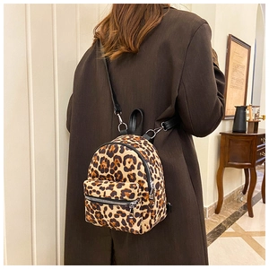 Detailed back view of a mini leopard print backpack on a model in a cozy indoor setting