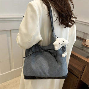 Borsa tote in denim grigio con finiture in pelle e ciondolo a nuvola indossata da modella