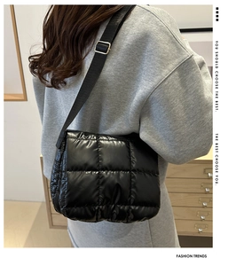 Detail of black quilted puffer bag showing glossy square texture and shoulder strap