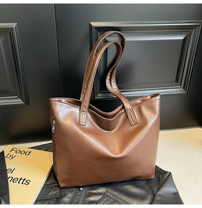 Detail of a brown large tote bag with lychee texture finish and side zipper accents