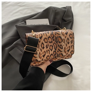Detail of leopard print crossbody bag featuring wide black strap and gold hardware