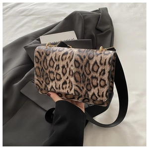 Detail view of leopard print crossbody bag featuring a black wide strap and golden hardware