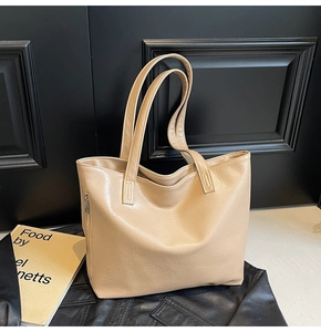 Detail view of large faux leather tote bag showing side zipper and soft texture in tan