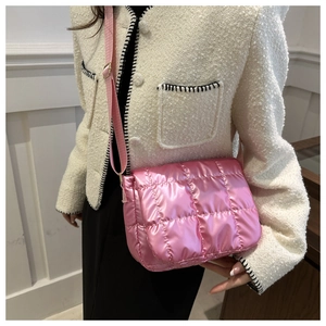 Close-up of pink quilted down-style crossbody bag with glossy finish and wide strap