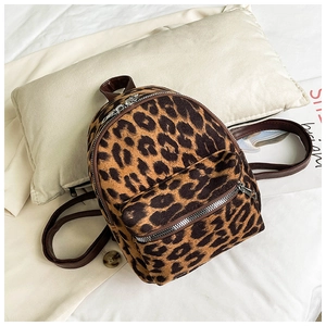 Detailed top view of leopard print faux suede mini backpack on soft white bedding