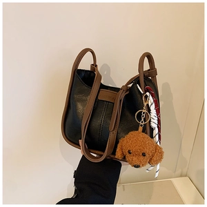 Detail of a large capacity tote with a teddy bear charm and textured leather finish