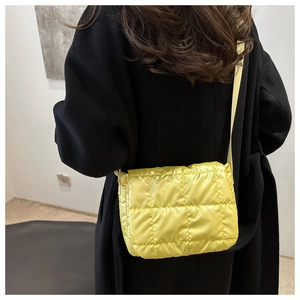 Detail of bright yellow quilted puffer tote bag worn cross-body over a dark winter coat