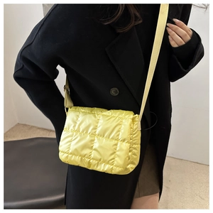 Close-up of bright yellow quilted puffer crossbody bag with glossy nylon texture