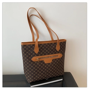 Detail of a large brown tote bag with geometric print and a front metal zipper pocket