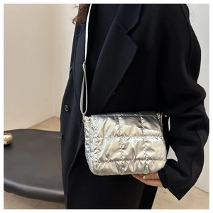 Chic silver metallic puffer crossbody bag with quilted pattern shown on a model