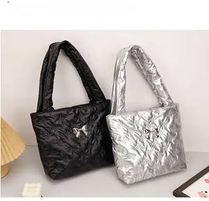 Detail of quilted puffer tote bags in black and silver with metallic bow accents