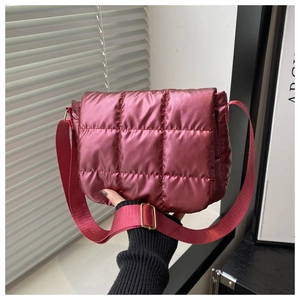 Detail of plum quilted puffer crossbody bag with metallic finish and wide strap
