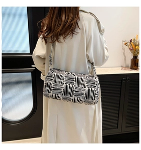 Detailed back view of a striped crossbody bag with a wide strap on a model's shoulder