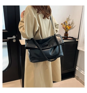 Detail of black PU leather tote featuring a thick woven rope handle and crossbody strap