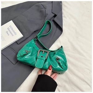Detail of bright green glossy PU leather underarm bag with decorative metal buckles