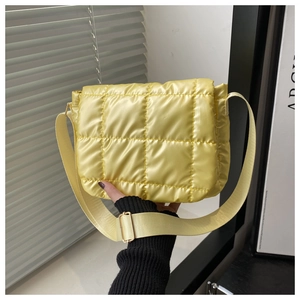 Detail of yellow quilted puff crossbody bag with wide strap and metallic buckle