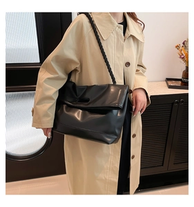 Detail of the soft black leather tote bag featuring a thick braided rope shoulder strap