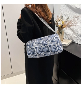 Detailed back view of a blue and white geometric cylinder tote with checkered strap