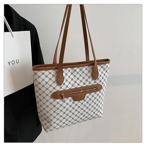 Close-up of geometric chain pattern and brown leather trim on a vintage tote bag