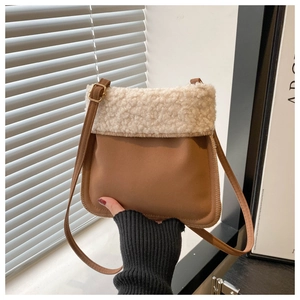 Close-up of stylish brown leather crossbody bag with fluffy cream lamb wool trim