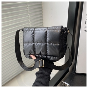 Detail of black quilted shoulder bag with glossy finish and gold metal buckle