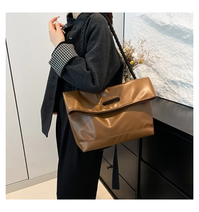 Detailed view of brown leather tote bag featuring a thick twisted rope shoulder strap