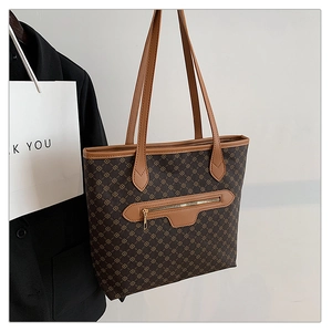 Close-up of brown tote bag with geometric pattern, leather trim and front zipper pocket