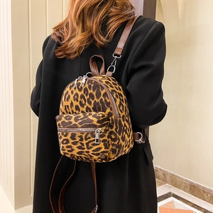 Fashionable leopard print faux suede backpack with brown leather straps worn by a model