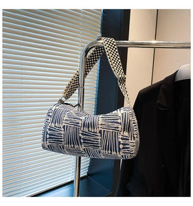 Detail of blue and white geometric woven cylinder bag with wide polka dot strap