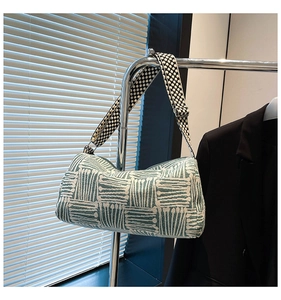 Close-up of green checkered nylon tote bag with polka dot wide strap on black blazer