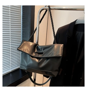 Detail of twisted rope shoulder strap and oval cutout handle on black tote bag