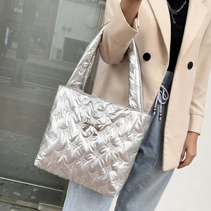 Silver metallic quilted tote bag with bow embroidery and metal bow accessory on front