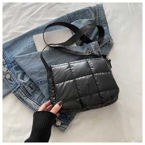 Detail of black quilted down shoulder bag with square stitching and wide nylon strap