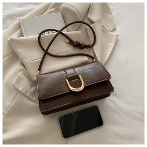Close-up of deep brown pebbled faux leather bag with golden U-shaped metal buckle