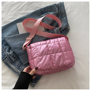 Detail of pink quilted puffy crossbody bag with glossy finish and wide adjustable strap