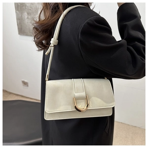 Detail view of cream white PU leather crossbody bag featuring a gold horseshoe metal buckle